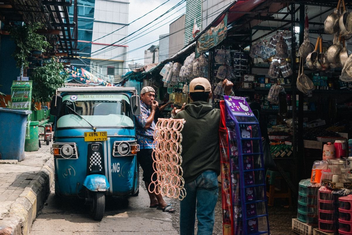 Street vendors and a motorised rickshaw in a busy market in East Jakarta