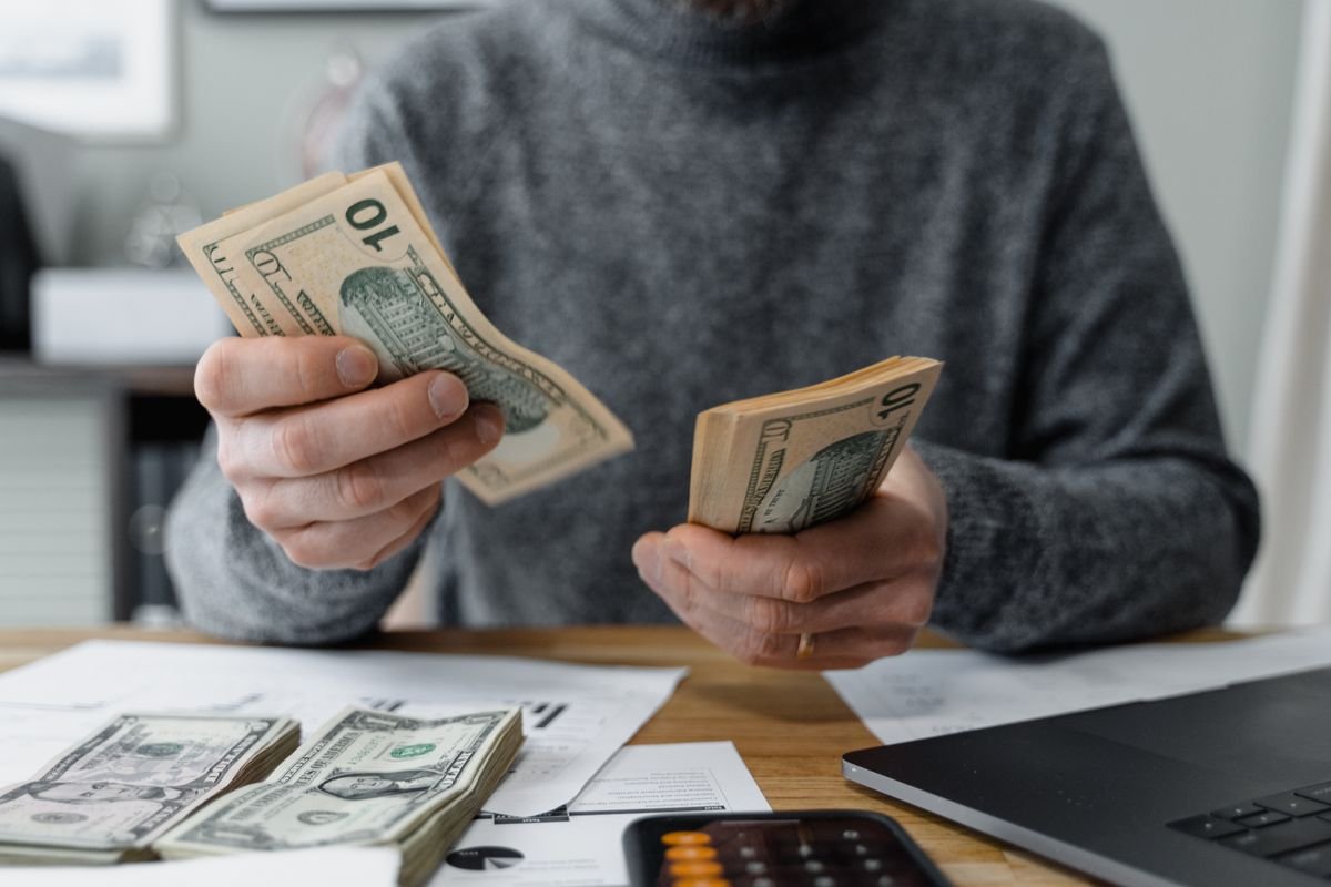 Counting banknotes beside a calculator and paperwork